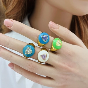 Close-up of four chunky gold rings with colorful enamel and triangular gemstones