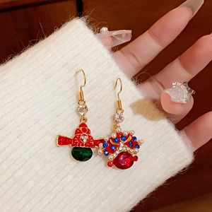 Detailed close-up of gold asymmetrical earrings with red enamel and green emerald accents