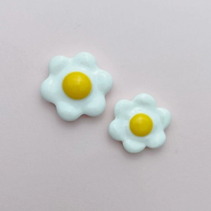 Close-up of small resin flower charms in white and yellow for DIY handmade crafts