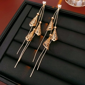 Détail de boucles d'oreilles dorées à pampilles avec pendentifs cônes sur plateau