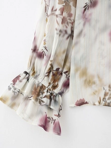 Dettaglio delle maniche a campana con strisce metalliche dorate e motivo floreale in chiffon