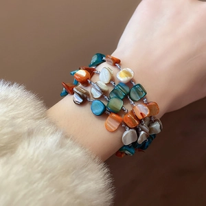 Detail of bohemian multilayer bracelet with colorful shell beads on a woman's wrist