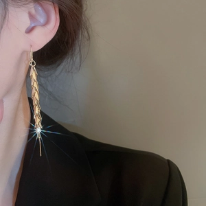 Detail of gold leaf fringe earrings with sparkling tassel design on a fashion model