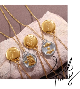 Close-up of gold 18K plated zodiac relief coin pendants on pink stone texture