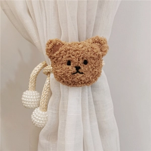 Detail of plush teddy bear curtain tieback with golden rope and large pearl accents