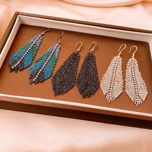 Three pairs of feather tassel earrings with rhinestones in blue, black, and gold colors