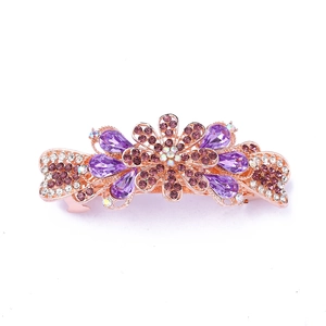 Macro shot of rose gold bow hair clip with purple rhinestones and crystal flower details