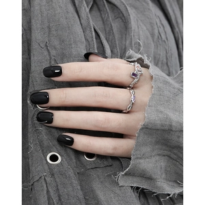 Silver geometric rhombus ring set with purple zircon gemstones on a grey fabric background