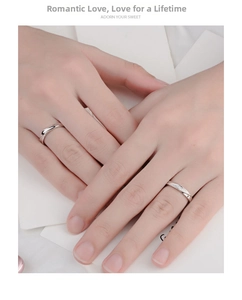Close-up of silver Mobius couple rings with sparkling stones on elegant crossed hands