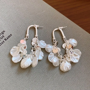 Détail macro de boucles d'oreilles argentées en U avec pétales de perles blanches