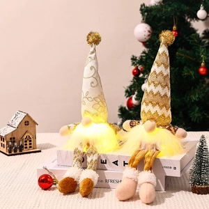 Lighted Christmas gnomes ornaments with gold knit hats and long legs on a festive set