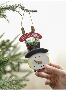 Close-up of hand hanging a wooden snowman ornament with Let It Snow banner on a Christmas tree