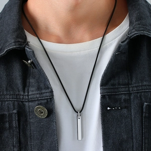Detail of silver tungsten bar pendant on black cord necklace worn by a male model