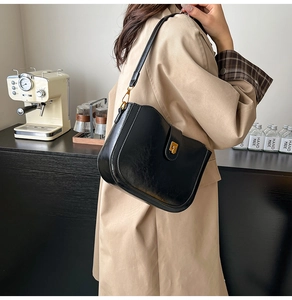 Close-up of black retro saddle bag with gold metal buckle and adjustable leather strap