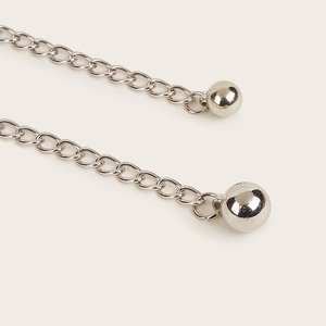 Macro shot of silver layered chains with smooth spherical pendants and metal finish