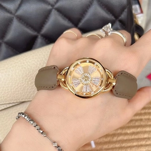 Close-up of a ladies' watch with a gold crystal dial and brown leather strap on wrist