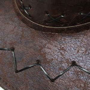 Macro view of vintage brown cowboy hat with distressed leather texture and cross stitching