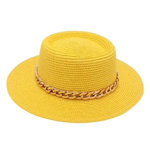 Detail of yellow straw sun hat featuring a wide flat brim and thick gold chain decoration