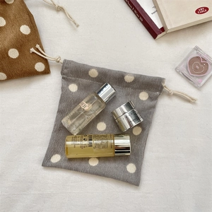 Close-up of corduroy polka dot drawstring pouch with cosmetics and soft lighting