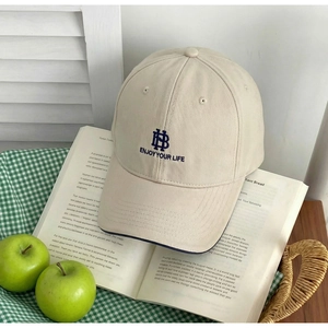 Detail of beige cotton baseball cap with blue HB embroidery on a classic book