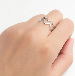 Detail of silver heart-shaped band ring with hollow pattern on model's finger