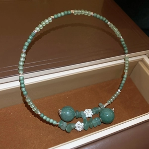 Dettaglio di perline di giada verde con fiori di loto argentati in una scatola