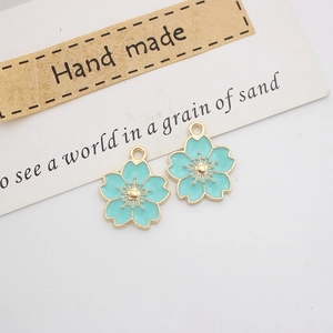 Detailed macro view of two light blue cherry blossom charms with gold-plated edges
