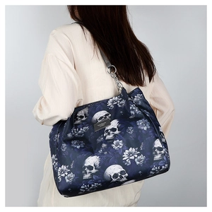 Detail of dark blue tote bag with skull and floral print featuring metal chain handles