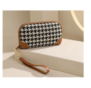 Detail view of houndstooth clutch bag with brown leather accents on a display stand