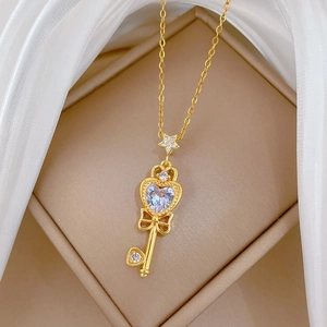 Detailed close-up of a gold bow key pendant necklace with sparkling heart-shaped zircon crystal