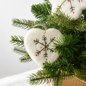 White wool felt heart ornament with green snowflake embroidery on a Christmas tree