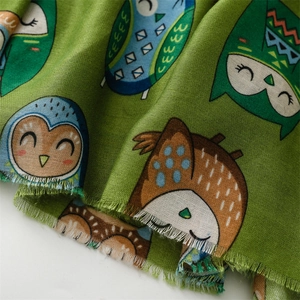 Detail of owl pattern on green cotton-linen scarf with natural frayed edges
