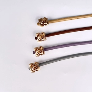 Detail view of thin leather belts with gold rose buckles in beige, brown, mauve, and grey