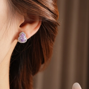 Close-up of a silver gourd-shaped earring with a pear-cut purple zircon and tiny crystals
