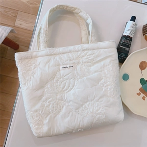 Detail of white quilted tote bag featuring 3D floral embroidery and a Simple Wish label