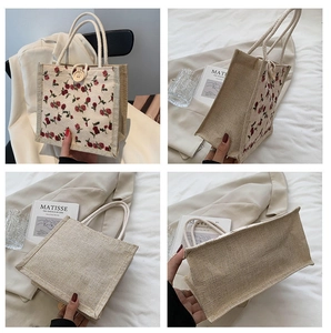 Detail of red rose print on linen tote bag with woven rope handles and wooden button