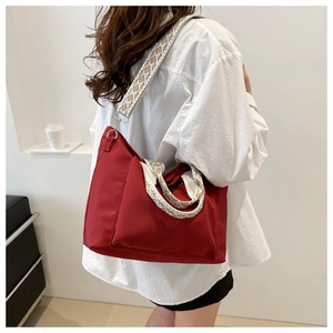 Red nylon tote bag featuring ethnic geometric pattern wide shoulder strap in a lifestyle view