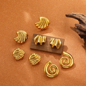 Detailed close-up of four chunky gold irregular textured metal earrings on a natural background