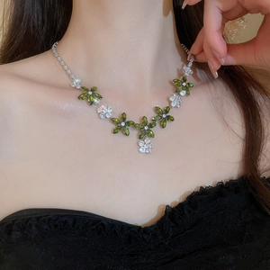 Gros plan du collier fleur en zircon avec pierres vertes et claires sur le mannequin