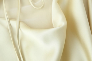 Close-up of champagne satin fabric showing elegant drape and silky texture of the dress