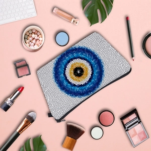 Water-resistant evil eye makeup bag with mosaic pattern and cosmetics on pink background