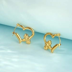 Detailed close-up of golden heart-shaped hoop earrings with 3D honey bee charms