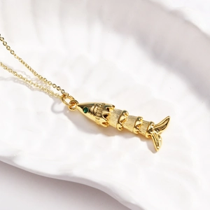 Detail of a vintage golden koi fish necklace with a green gemstone eye in a shell tray