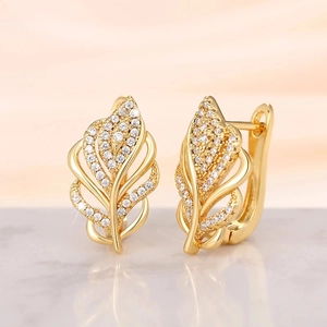Macro shot of gold wheat ear earrings featuring white cubic zirconia on marble surface