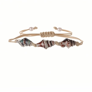 Detail of hand-woven shell bracelet with reddish-brown spotted shells and pearl accents