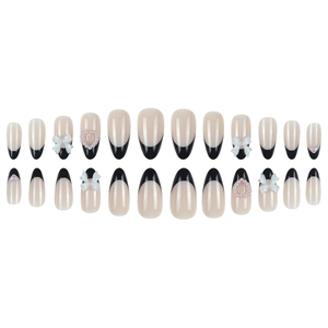 French tip press-on nails with black bows and pearl heart accents in nude pink color