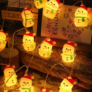 LED snowman string lights with red hats and green scarves on a wooden festive background