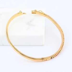 Detailed close-up of an 18k gold plated oval bangle with multi-colored cubic zirconia stones