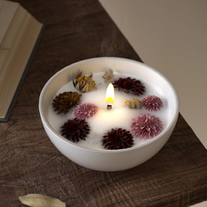 Macro shot of a lit floral scented candle with dried petals in a white ceramic bowl