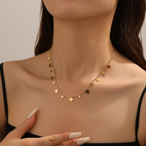 Minimalist gold necklace with geometric square pendants on a thin chain worn by a model